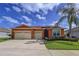 Charming single-story home with a three-car garage, well-maintained landscaping, and an orange painted stucco facade at 11614 Ashton Field Ave, Riverview, FL 33579