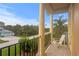 A balcony with large white pillars, a black metal railing, and a chair facing a landscape of green trees at 131 Miramar Ne Blvd, St Petersburg, FL 33704