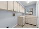 Laundry room with white cabinets, a utility sink, and a window for natural light at 14164 Fennsbury Dr, Tampa, FL 33624