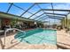 Screened-in pool area features a sparkling pool, lush landscaping, and comfortable outdoor seating at 159 Canby Cir, Spring Hill, FL 34606