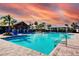 Resort-style pool with cabanas, palm trees, and lounge chairs under a vibrant sunset sky at 16425 66Th E Ln, Parrish, FL 34219