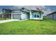 Well-maintained single-story home featuring a manicured lawn, gray garage door, and teal-colored accents at 16425 66Th E Ln, Parrish, FL 34219