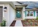 Inviting front porch with a teal-colored door, stylish lighting, and well-maintained landscaping at 16425 66Th E Ln, Parrish, FL 34219