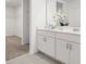Bright bathroom with double sinks, white cabinets, and an open walk-in closet with shelving at 1829 Draughton Dr, Zephyrhills, FL 33541