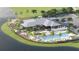 Aerial view of a resort-style clubhouse featuring a pool, lounge area, umbrellas, and tropical landscaping by a lake at 18421 Vista Park Ter, Venice, FL 34293