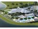 Aerial view of a clubhouse with a pool, patio, parking, lounge chairs and lush tropical landscaping near a pond at 18421 Vista Park Ter, Venice, FL 34293
