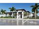 A modern clubhouse with a grand entrance, black framed windows, lush landscaping, and parking in front of the building at 18421 Vista Park Ter, Venice, FL 34293