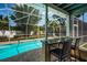 Screened-in pool area with swim-up bar and two stools overlooking lush backyard at 2020 58Th N Way, Clearwater, FL 33760