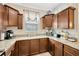 An L-shaped kitchen featuring granite countertops, wooden cabinets, and modern appliances at 2022 Hawks View Dr, Ruskin, FL 33570