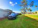 This front yard has a well-manicured lawn, mature trees, and a paved driveway to a carport at 22798 Penny Loop, Land O Lakes, FL 34639