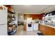 Cozy kitchen featuring wood cabinets, white appliances, tile floors and a pass through window to an additional living space at 22798 Penny Loop, Land O Lakes, FL 34639