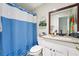Well-lit bathroom featuring a white vanity, granite countertop, modern fixtures, and a shower with a blue curtain at 2714 Witley Ave, Palm Harbor, FL 34685