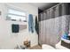 Cozy bathroom features a shower with patterned shower curtain, small window, and woven basket at 2714 Witley Ave, Palm Harbor, FL 34685