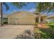 Charming yellow home with a three-car garage, landscaped front yard, and well-maintained curb appeal at 2957 Hickory Grove Dr, Valrico, FL 33596