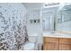 Well-lit bathroom with a shower featuring a curtain, and a vanity with drawers and shelves at 31349 Philmar Ln, Wesley Chapel, FL 33543