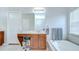 Well-lit bathroom with wooden vanity, soaking tub with tile surround, and separate toilet area at 31349 Philmar Ln, Wesley Chapel, FL 33543