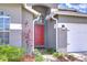 Inviting entrance featuring a red front door, manicured landscaping, and a two-car garage at 31349 Philmar Ln, Wesley Chapel, FL 33543