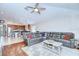Spacious living room open to the kitchen featuring hardwood floors, ceiling fan, and comfortable gray sofa at 31349 Philmar Ln, Wesley Chapel, FL 33543