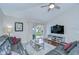 Comfortable living room features hardwood flooring, ceiling fan, large TV, and sliding glass doors to the patio at 31349 Philmar Ln, Wesley Chapel, FL 33543