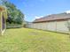 Wide shot of a fenced in yard with a large tree in the corner and green grass throughout at 3824 Duke Firth St, Land O Lakes, FL 34638