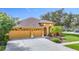 Inviting home featuring a two-car garage, manicured landscaping, and charming arched entryway at 3824 Duke Firth St, Land O Lakes, FL 34638