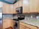 Well-lit kitchen features granite countertops, stainless steel appliances, and natural wood cabinets at 3824 Duke Firth St, Land O Lakes, FL 34638