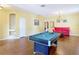 Open-concept living area with hardwood floors, billiards table, and a comfortable red couch at 3824 Duke Firth St, Land O Lakes, FL 34638