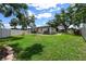 Fenced backyard with mature trees, green grass, and a play structure at 4124 Herrick Ln, Sarasota, FL 34241