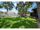 Fenced backyard with mature trees and lush green grass and a play structure at 4124 Herrick Ln, Sarasota, FL 34241