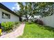 View of the backyard with paver walkway, green grass, garden beds and mature trees at 4124 Herrick Ln, Sarasota, FL 34241
