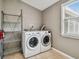 Neutral laundry room with washer, dryer, tile floor, shelving unit, and window at 535 6Th N St, St Petersburg, FL 33701