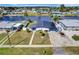 Aerial view of a waterfront home with modern architecture, a dark roof, a well kept lawn, and boat access at 551 Lindley Ter, Port Charlotte, FL 33952