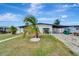 Charming home with well-maintained landscaping, mature palm trees, and a covered carport for convenient parking at 551 Lindley Ter, Port Charlotte, FL 33952