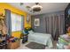 Bright bedroom with a cozy bed, ceiling fan, colorful accents, and eclectic decor on yellow and gray walls at 5826 Taywood Dr, Tampa, FL 33624