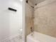 Bathroom featuring a shower over the tub with travertine tile and a decorative towel rack at 6682 Mauna Loa Blvd, Sarasota, FL 34241