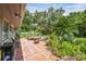Landscaped backyard with a tile patio, lush plantings, mature trees, and a dining table at 7219 4Th N Ave, St Petersburg, FL 33710