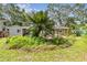 Landscaped backyard with a gray house and a patio with outdoor seating nestled amongst mature trees and lush greenery at 7219 4Th N Ave, St Petersburg, FL 33710