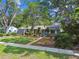 Charming single-story home featuring a well-manicured lawn, mature trees, and blue front door enhancing its curb appeal at 7219 4Th N Ave, St Petersburg, FL 33710