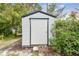 White shed with black trim and single door in a lush, landscaped backyard at 7219 4Th N Ave, St Petersburg, FL 33710