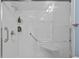 Accessible shower with glass doors, grab bars, and built-in shelving at 7705 4Th W Ave, Bradenton, FL 34209