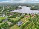 Overhead shot of sprawling estate with tennis court and pool, bordered by mature trees and a serene lake at 8410 Kenavis Pl, Odessa, FL 33556