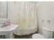 This bathroom features a classic sink, a toilet, and a shower with a decorative curtain and tile flooring at 8410 Kenavis Pl, Odessa, FL 33556