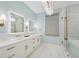 Bright bathroom featuring dual vanities, marble floors, bronze hardware, and a glass enclosed shower at 8410 Kenavis Pl, Odessa, FL 33556