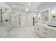 A luxurious bathroom featuring marble floors, a glass enclosed shower, and a double vanity with brass fixtures at 8410 Kenavis Pl, Odessa, FL 33556