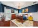 This bedroom has wood floors, blue walls, two windows, decorative artwork, and an area rug at 8410 Kenavis Pl, Odessa, FL 33556