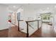 Upstairs hallway featuring hardwood floors, white trim and railings, and decorative shelving with natural light at 8410 Kenavis Pl, Odessa, FL 33556