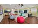 Entertainment room with a gray sofa, colorful rug, mounted televisions, and wood floors at 8410 Kenavis Pl, Odessa, FL 33556