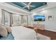 Bright main bedroom with a tray ceiling, a large bed, and a beautifully appointed dresser with wall mounted television at 8410 Kenavis Pl, Odessa, FL 33556