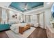 Bright main bedroom featuring a tray ceiling, ceiling fan, and ample natural light from the many windows at 8410 Kenavis Pl, Odessa, FL 33556