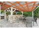 Outdoor kitchen and dining area with a grill, seating, stone countertops, and a mounted TV for entertainment at 8410 Kenavis Pl, Odessa, FL 33556